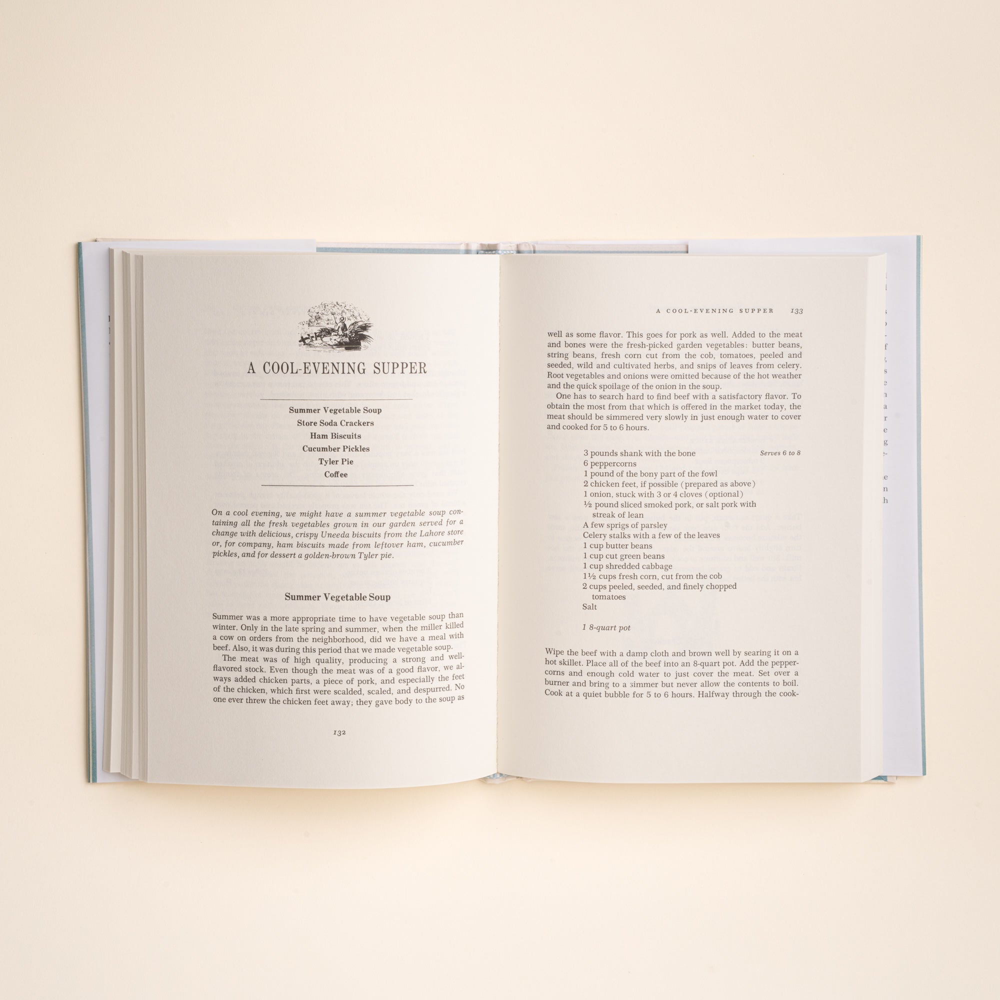 An open hardcover cookbook spread showing a recipe page for 'A Cool Evening Supper' on warm off-white paper, photographed against a matching light cream background.