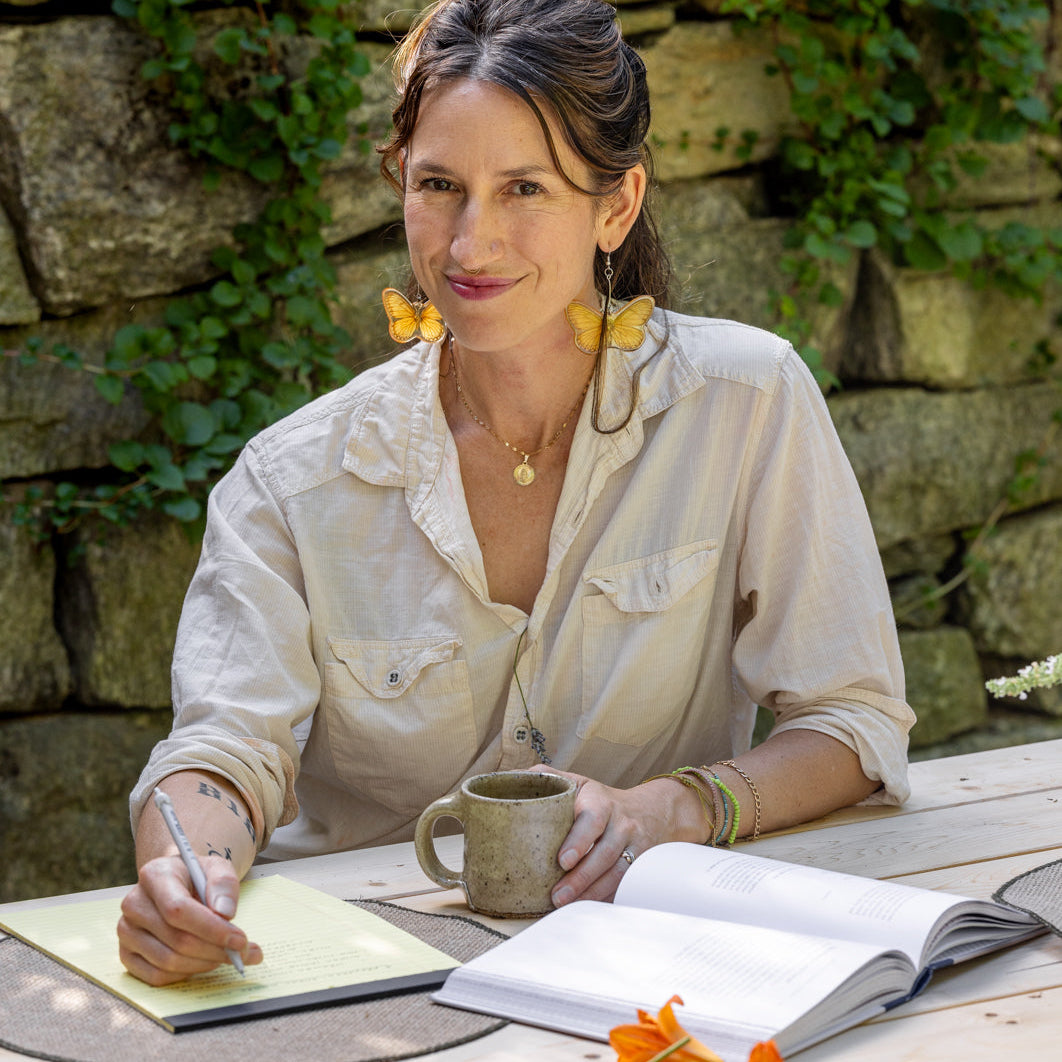Connie sitting at a table outside reading Taste of Country Cooking and writing on a yellow notepad