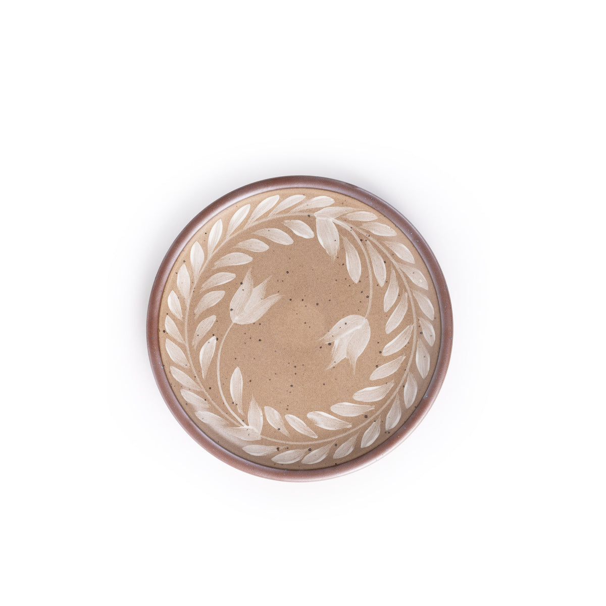 Side round ceramic plate with a hand-painted white leaf wreath and floral design on a warm pale brown background with an exposed clay rim.