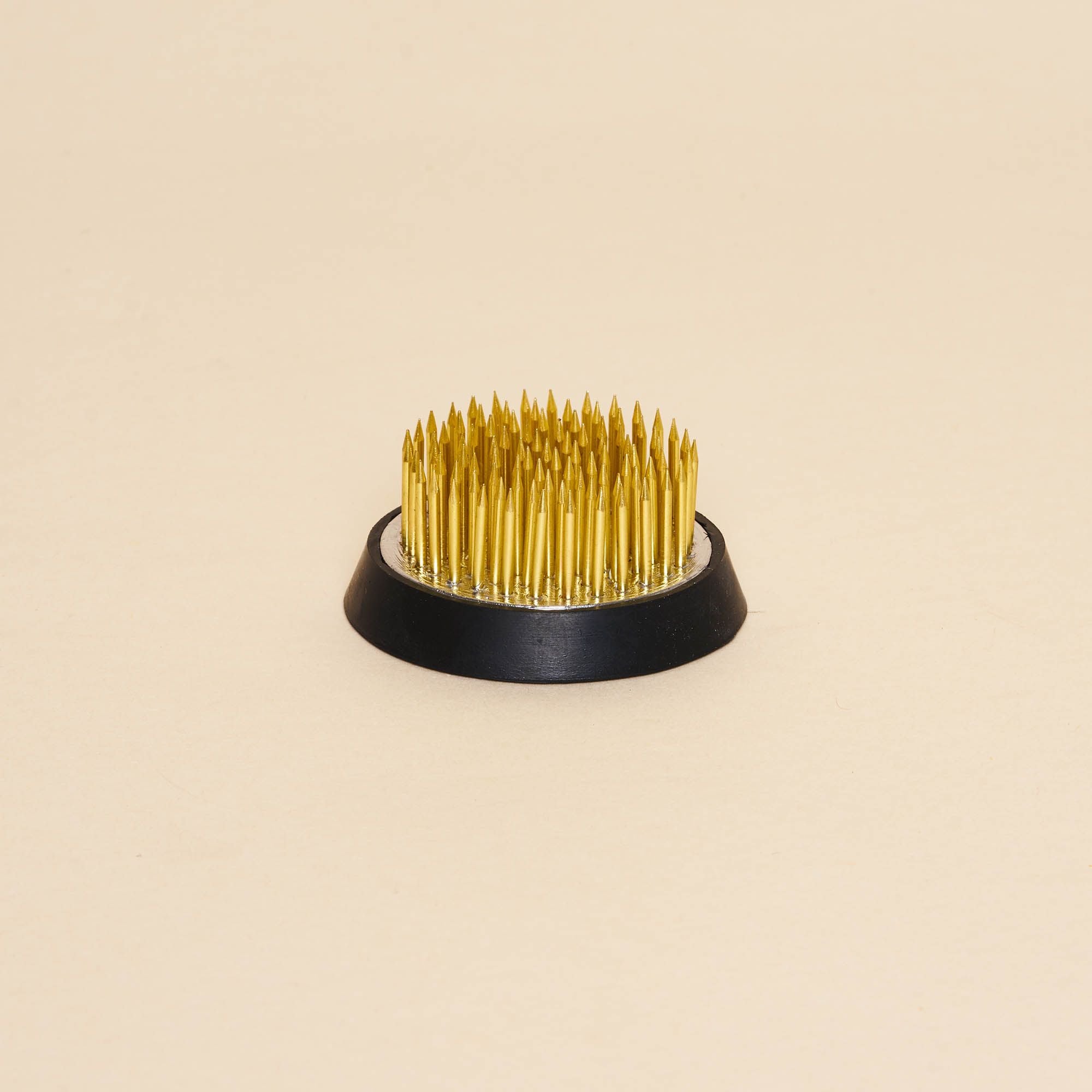 A small "kenzan" – a pin frog made of brass spikes on a flat circular base to assist in flower arrangements.