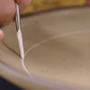 A video of Rachel painting the tulip crown design on ceramic dinnerware in a pottery factory setting